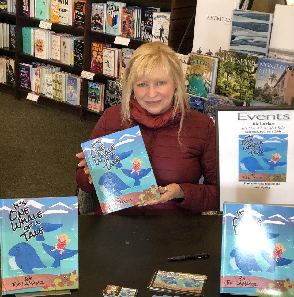 Rie Lamarr posing next to her book at her book signing for It's One Whale of a Tale