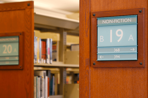 Un cartel azul claro que dirige a los usuarios de una biblioteca hacia los libros de no ficción.