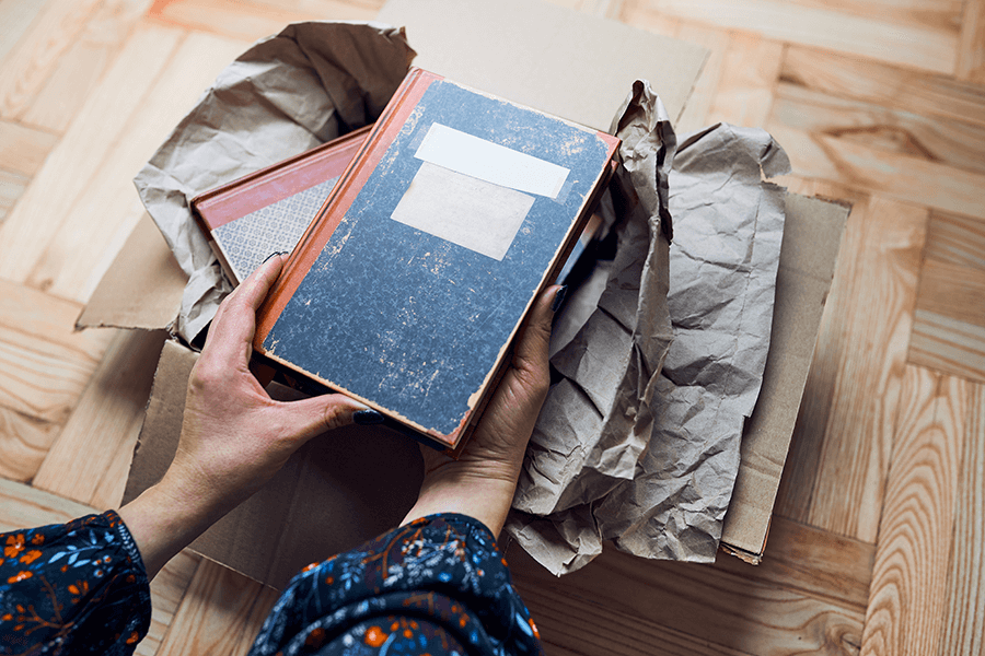 Photo of a woman's hands taking books out of cardboard box