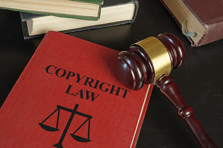 copyright book next to a courtroom gavel resting on a dark wood table