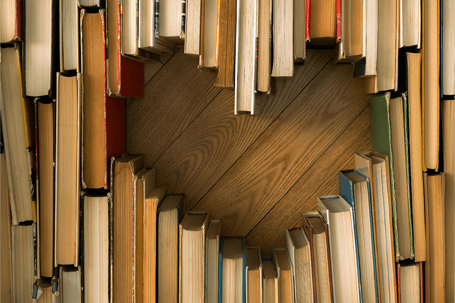 Books assorted on a wooden table in the shape of a heart