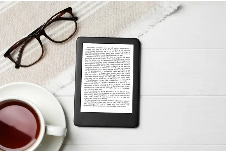 E-reader displaying a page of text on a white counter alongside glasses and coffee