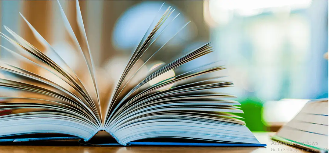 open flat book with a blue cover and the pages fanned out on a desktop