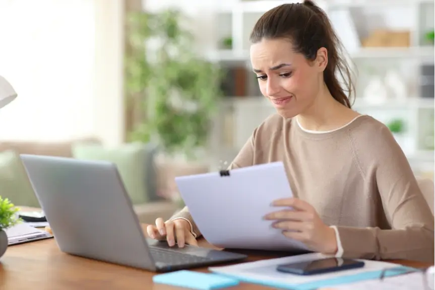 woman reading a contract while sitting at her laptop